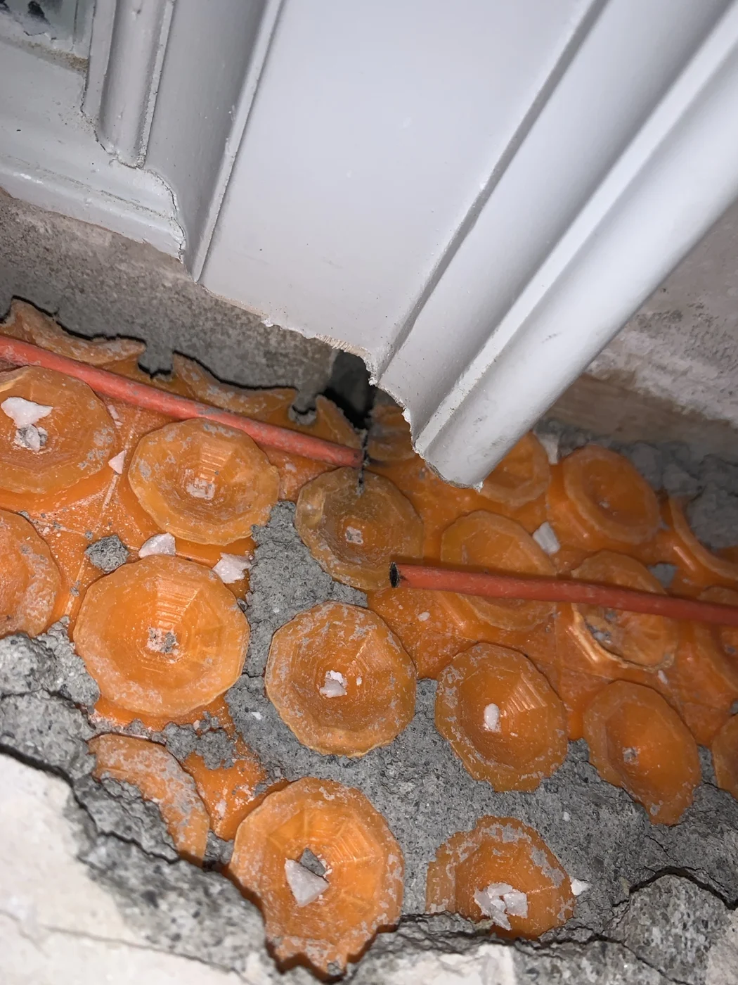 Exposed orange heating cable with a visible break beside a door frame