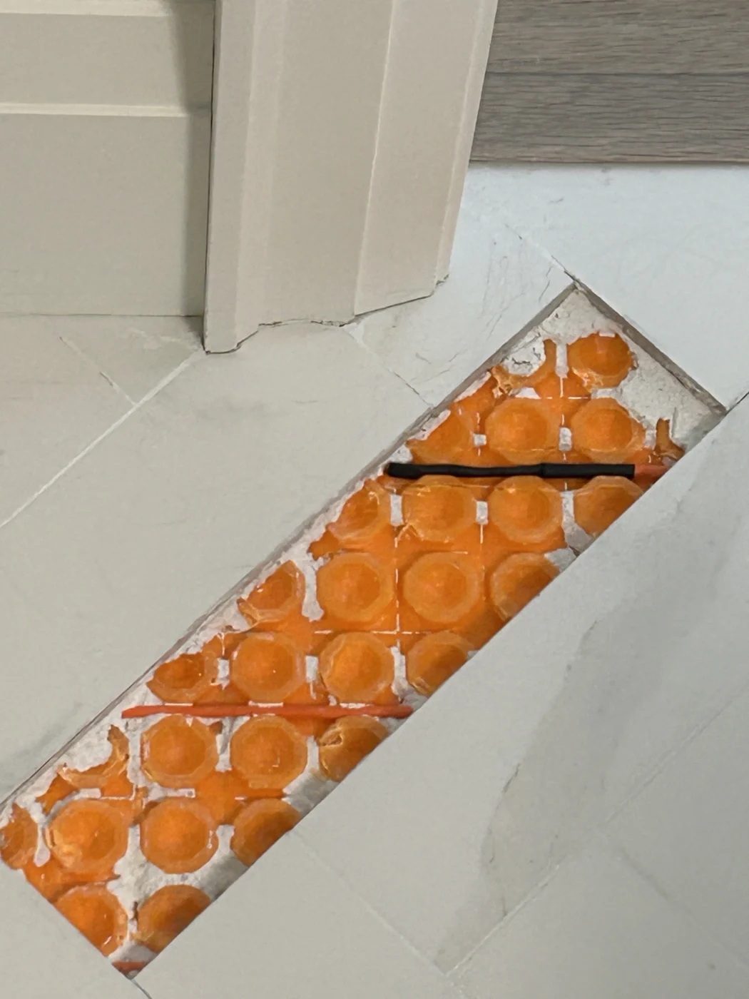 Black sleeved heating cable repair within a narrow opening in a tiled floor