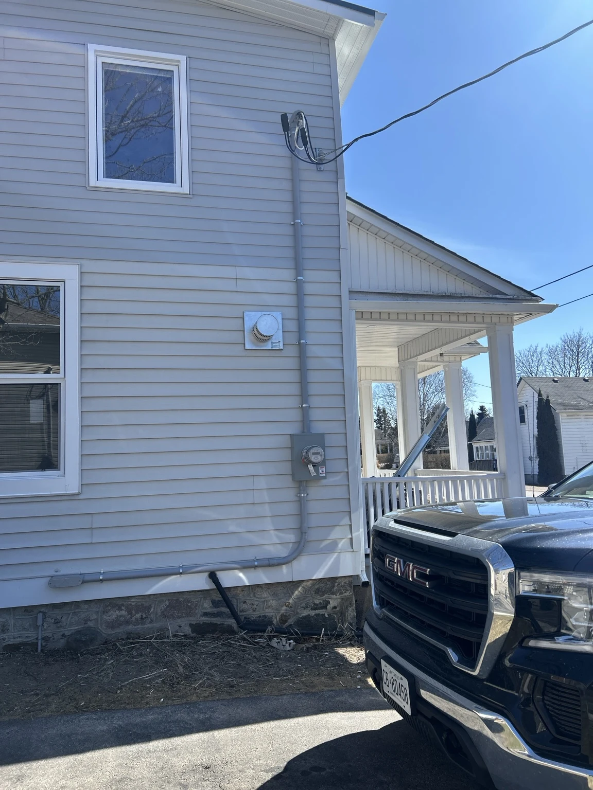 Exterior electrical meter, overhead service connection and conduit routing on a home with siding