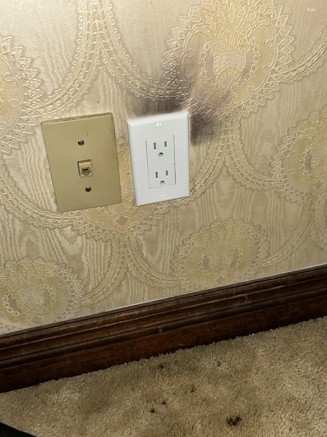 New white receptacle and cover plate installed where the damaged outlet was located, with existing burn marks still visible