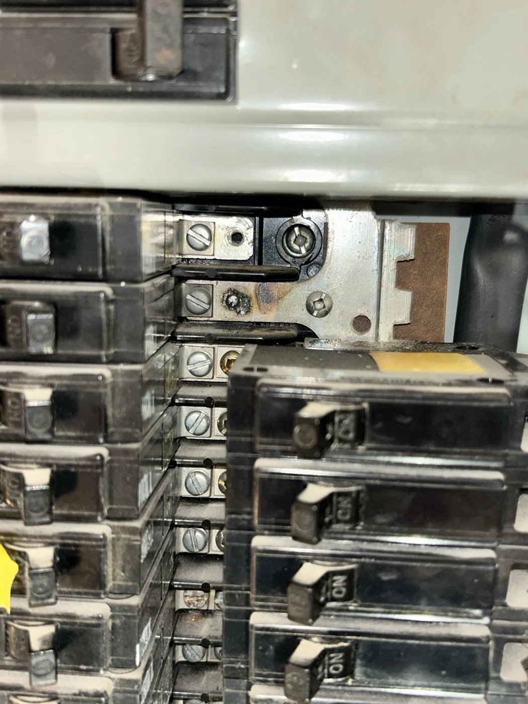 Exposed electrical panel connection with a dark damaged contact point and surrounding discoloration